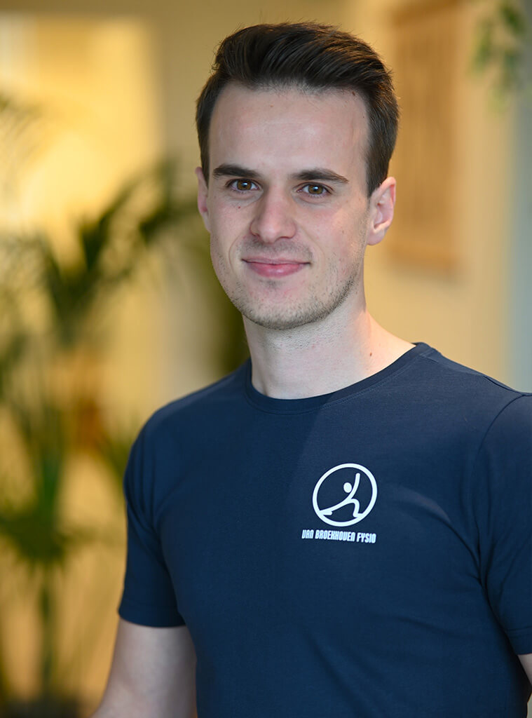 Tom Duys is fysiotherapeut en draagt een donkerblauw shirt