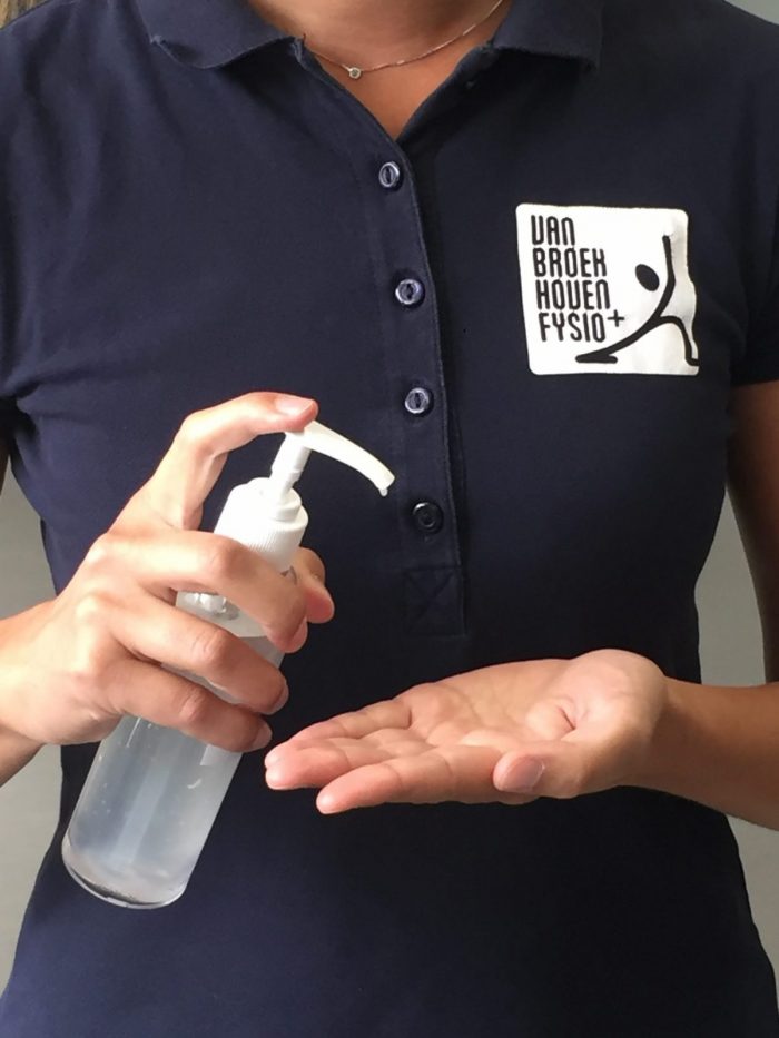Een fysiotherapeut heeft een flesje met ontsmettingsmiddel vast