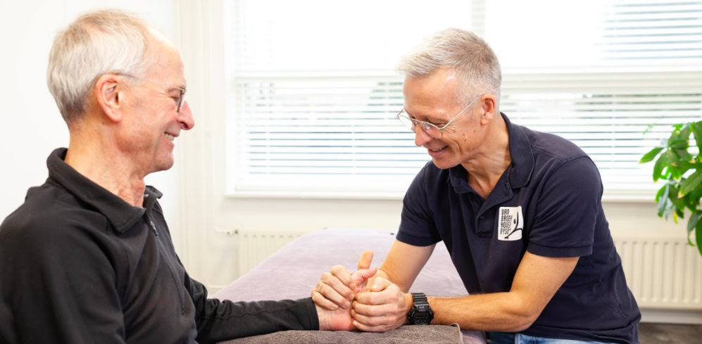 Fysiotherapeut van Van Broekhoven helpt een man met een fietsershand