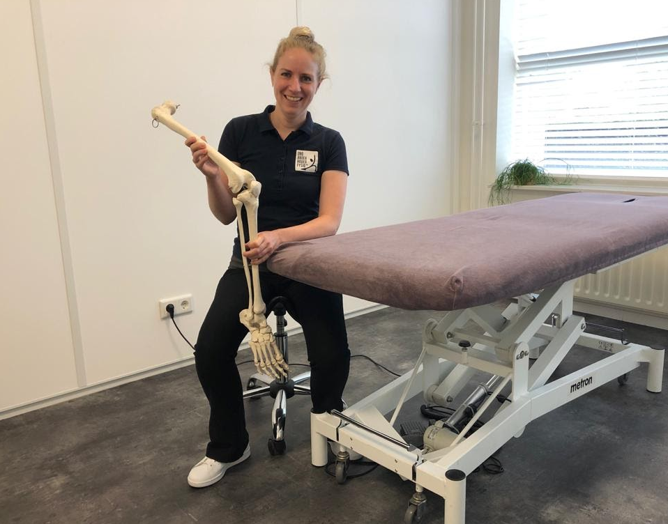 Fysiotherapeut van Van Broekhoven legt uit met een skelet hoe het kniegewricht werkt om knieartrose uit te leggen